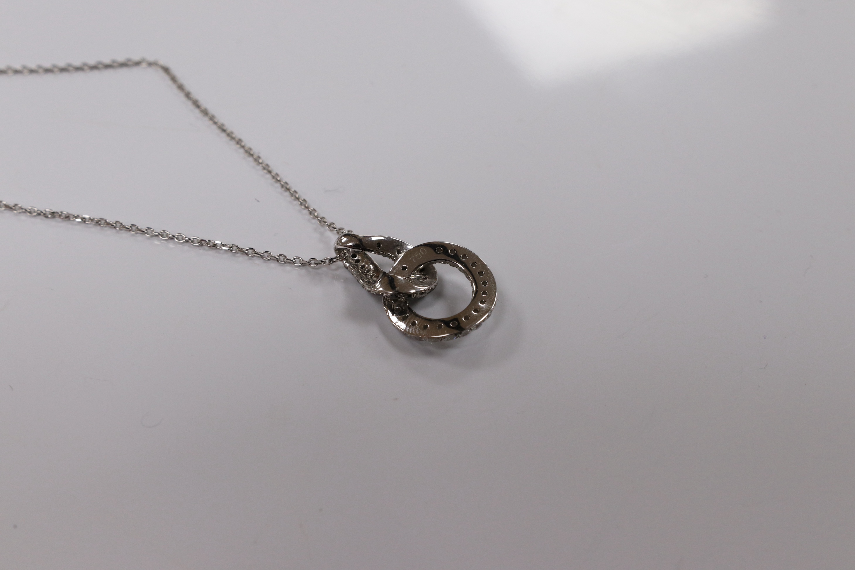 A modern 18k white metal and diamond chip set double loop pendant, 20mm, on an 18k white metal chain, 40cm, gross weight 4.1 grams. Condition - fair